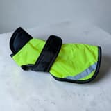 Reflektor detalj Hundjacka: a lime-green dog jacket with dark edging and a reflective strip.