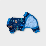 Detaljbild på mörkblå hundpyjamas med lekfullt dinosauriemotiv och mjukt tyg.