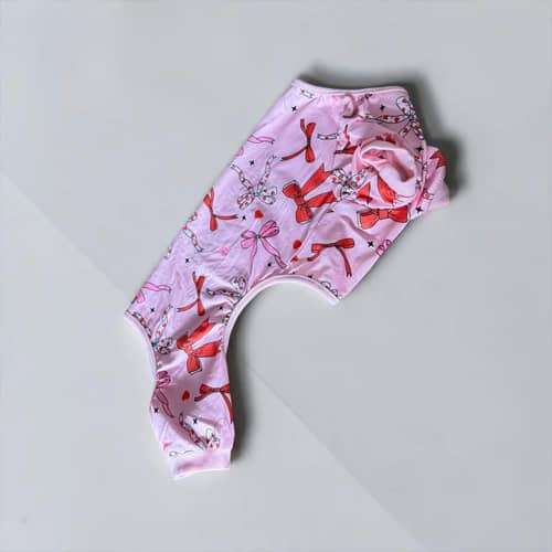 Rosettdröm Hundpyjamas, a pale pink dog garment patterned with red bows.