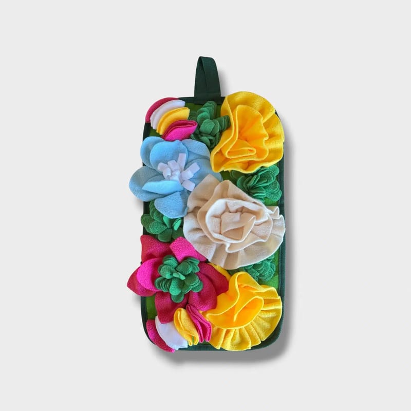 Närbild på en färgglad hundsnusmatta med blommigt mönster, perfekt för fodersök och mental stimulans.